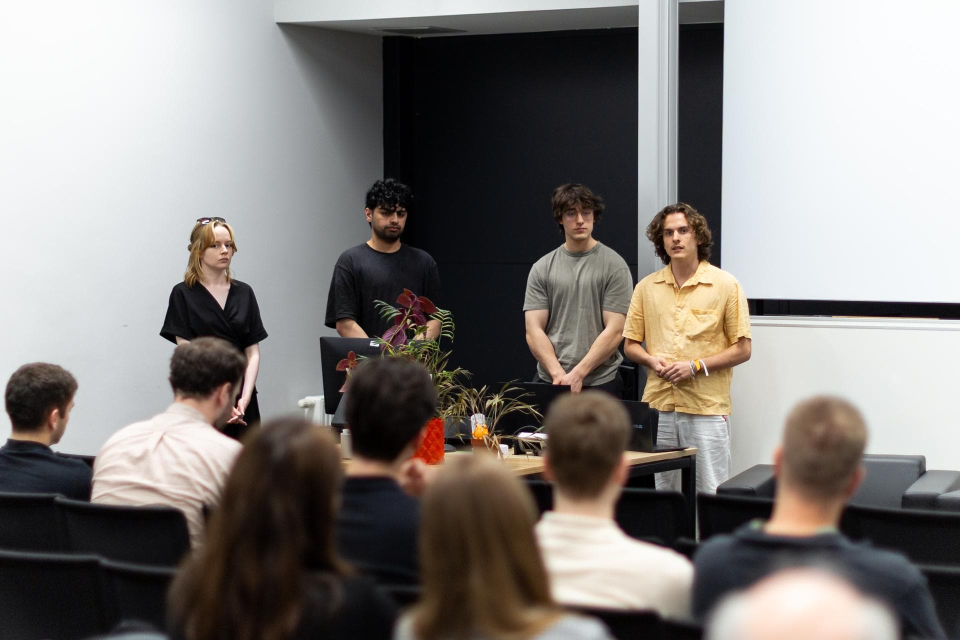 The four of us presenting Sprooty to a room of people, with plants and a frog on the table.